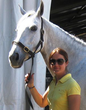 Photo of Morgan Kent in front of large white horse